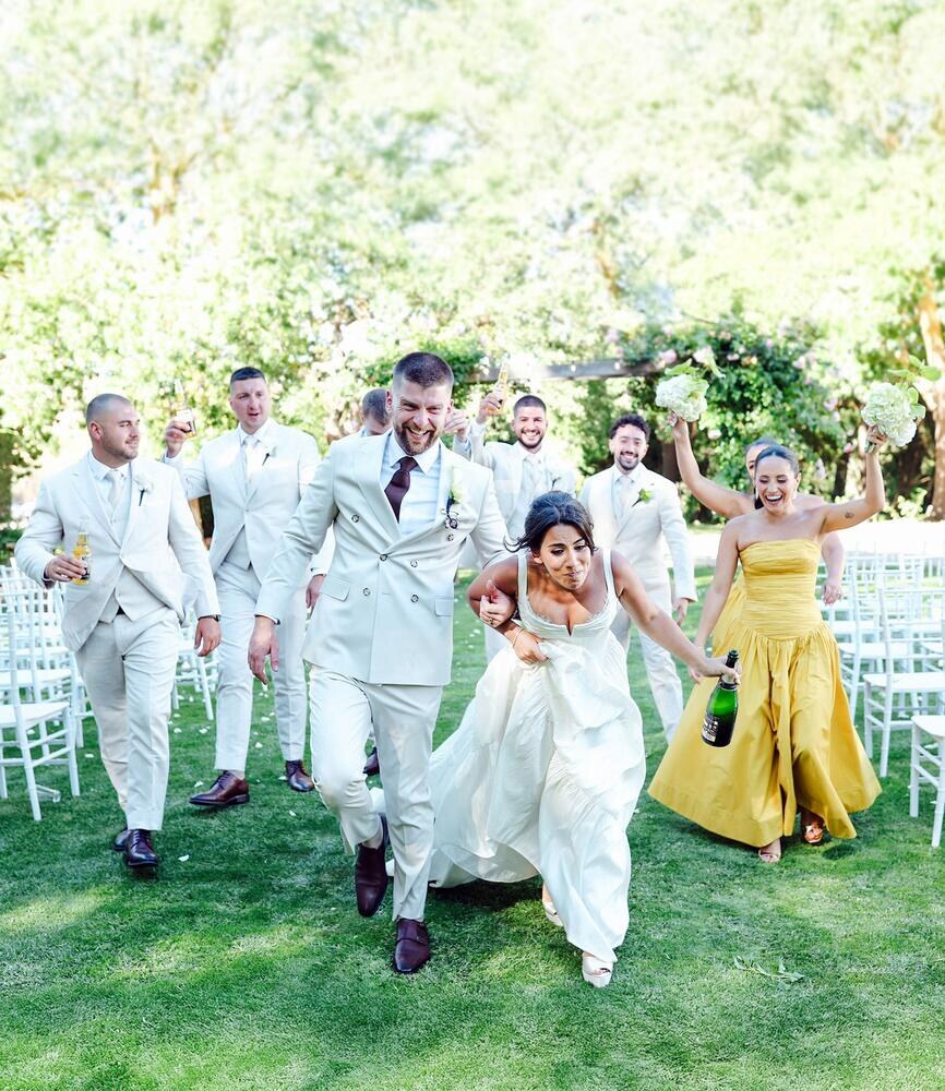 A wedding party running and laughing with champagne