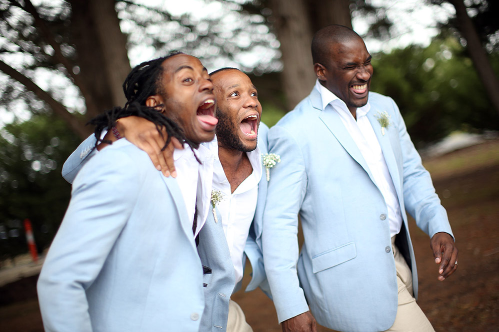 Three groomsmen laughing together outdoors