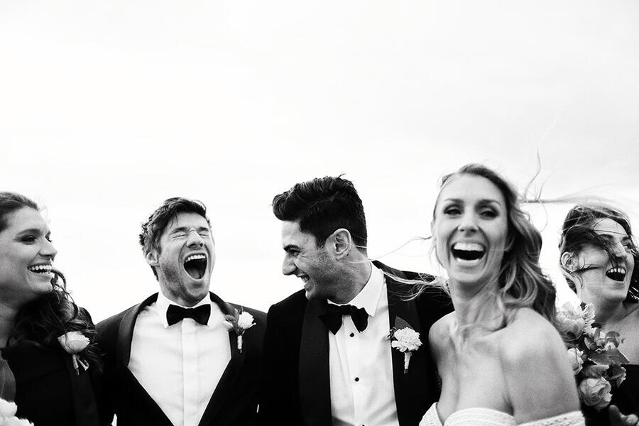 Wedding party laughing together in a candid black and white photograph