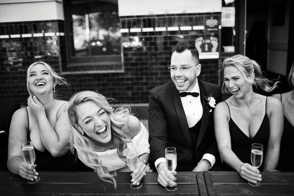 Lauren and Haydn laughing with friends at their wedding