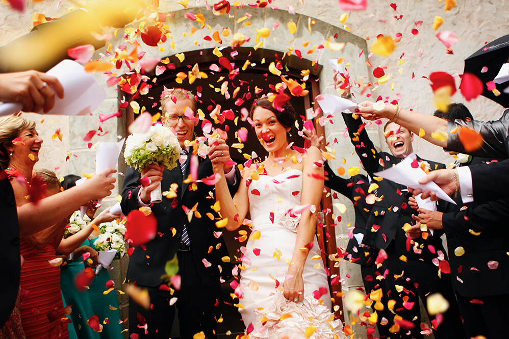 Newlyweds celebrating beneath a shower of colourful petals