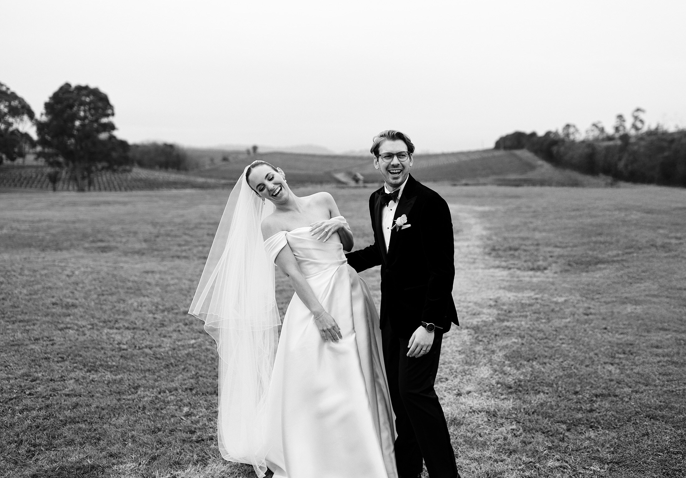 Newlyweds laughing together in a vineyard