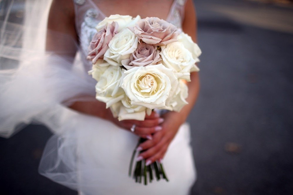 A bride holding a bouquet of white and pale pink roses during her wedding.