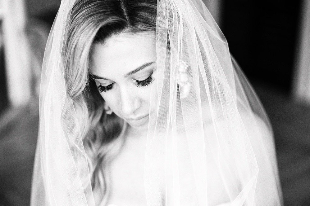A woman with long hair wearing a veil looking down, black and white photo.