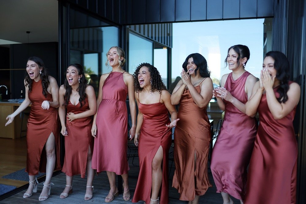 Group of women in matching dresses laughing and celebrating indoors