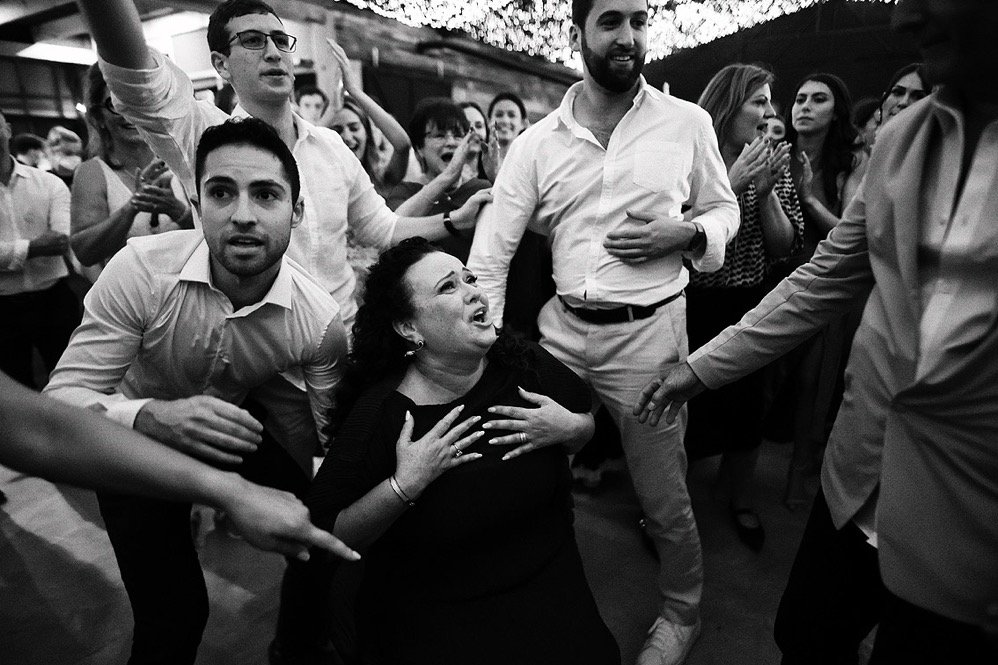 People dancing and celebrating at an event, with a woman appearing distressed in the center.