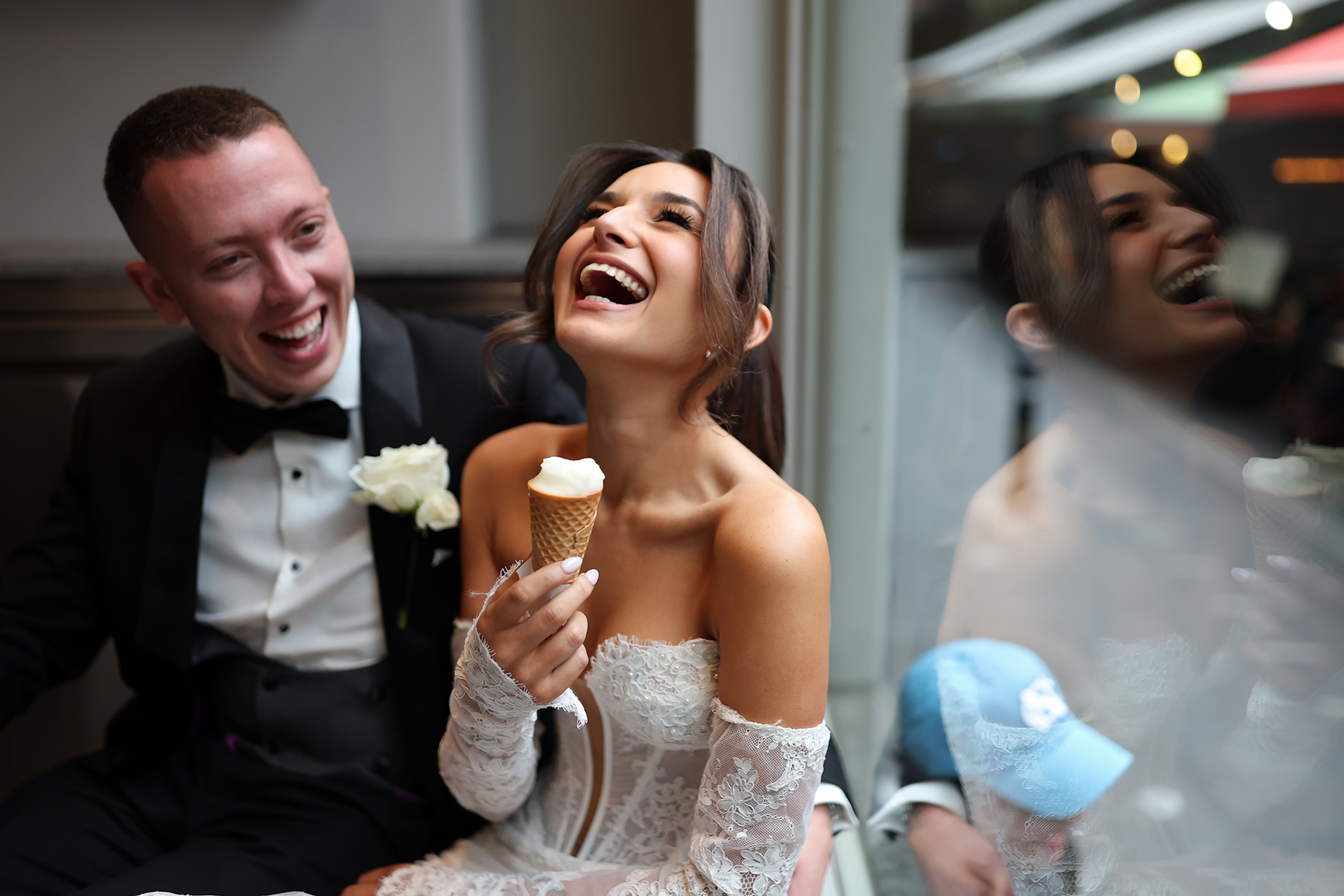 Bride and groom laughing together over an ice cream on their wedding day